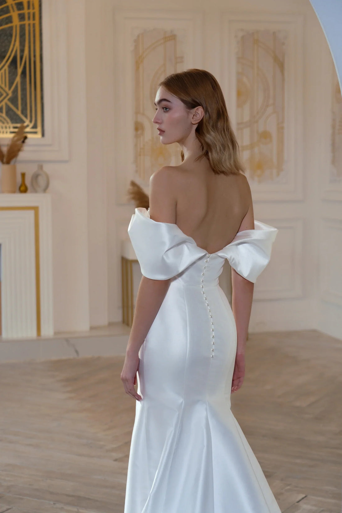 A fitted wedding dress with dropped straps and an embroidered bodice.